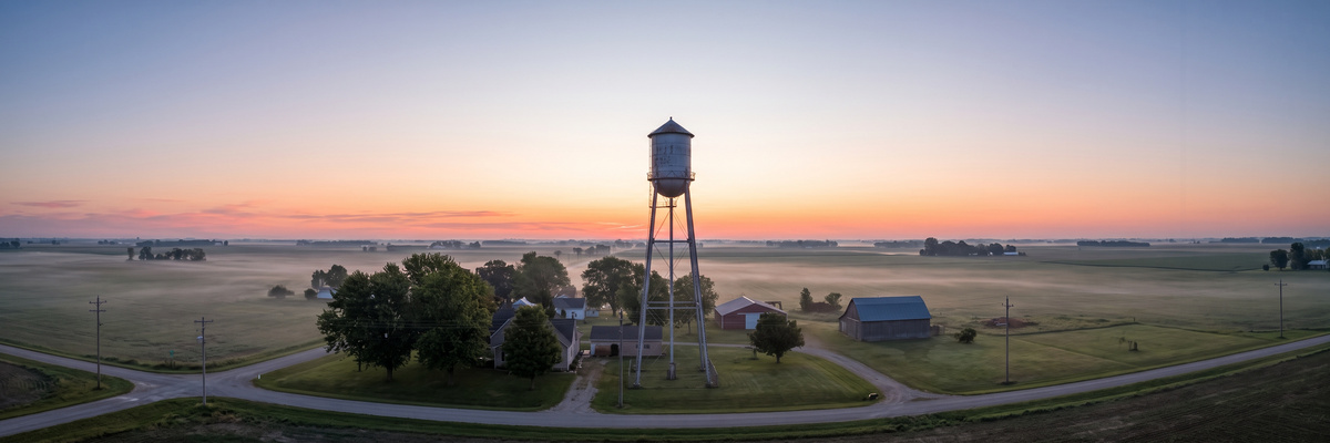 Rural water tower above a small farm town at sunrise