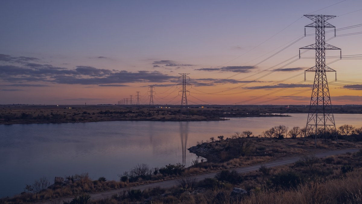 Electric transmission lines crossing a reservoir on the Texas plains at dusk